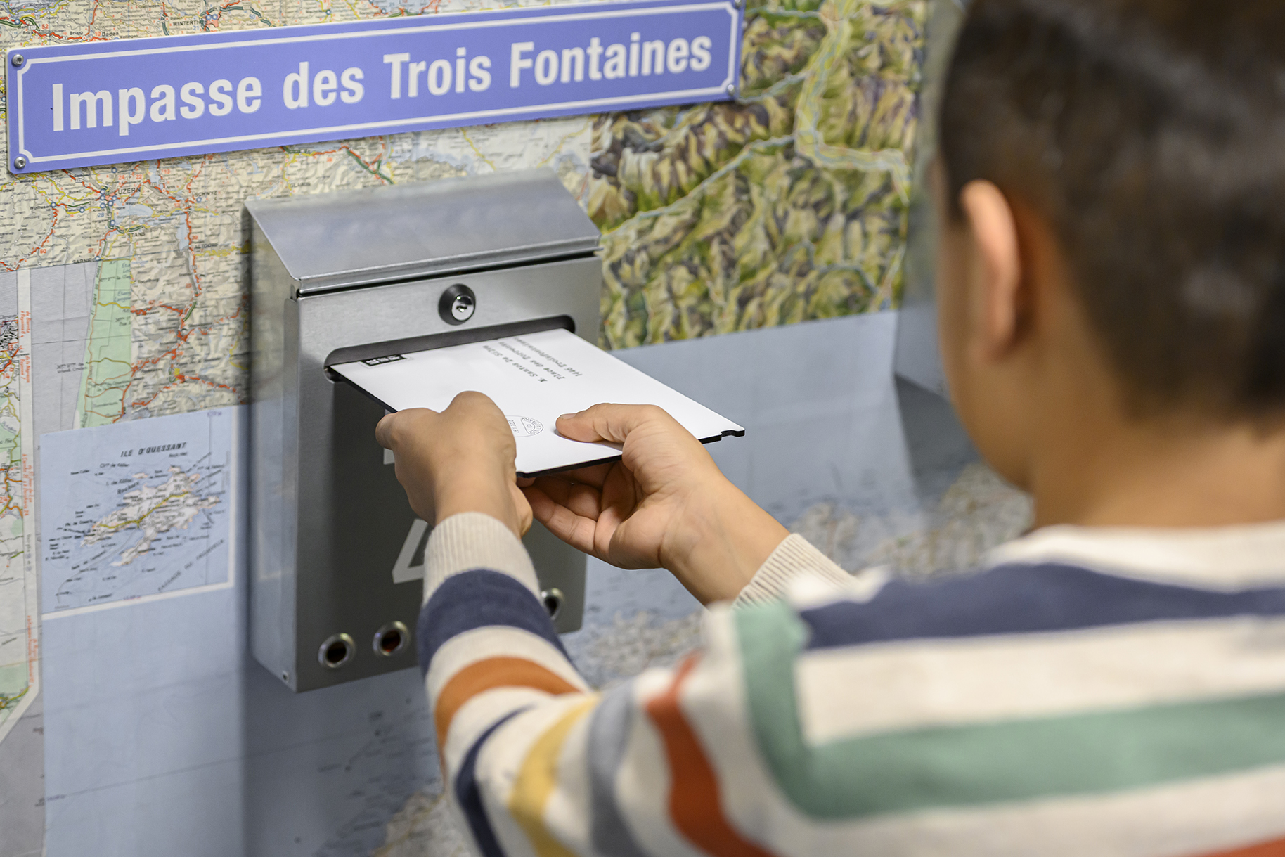 Un enfant met une lettre dans une boite aux lettres